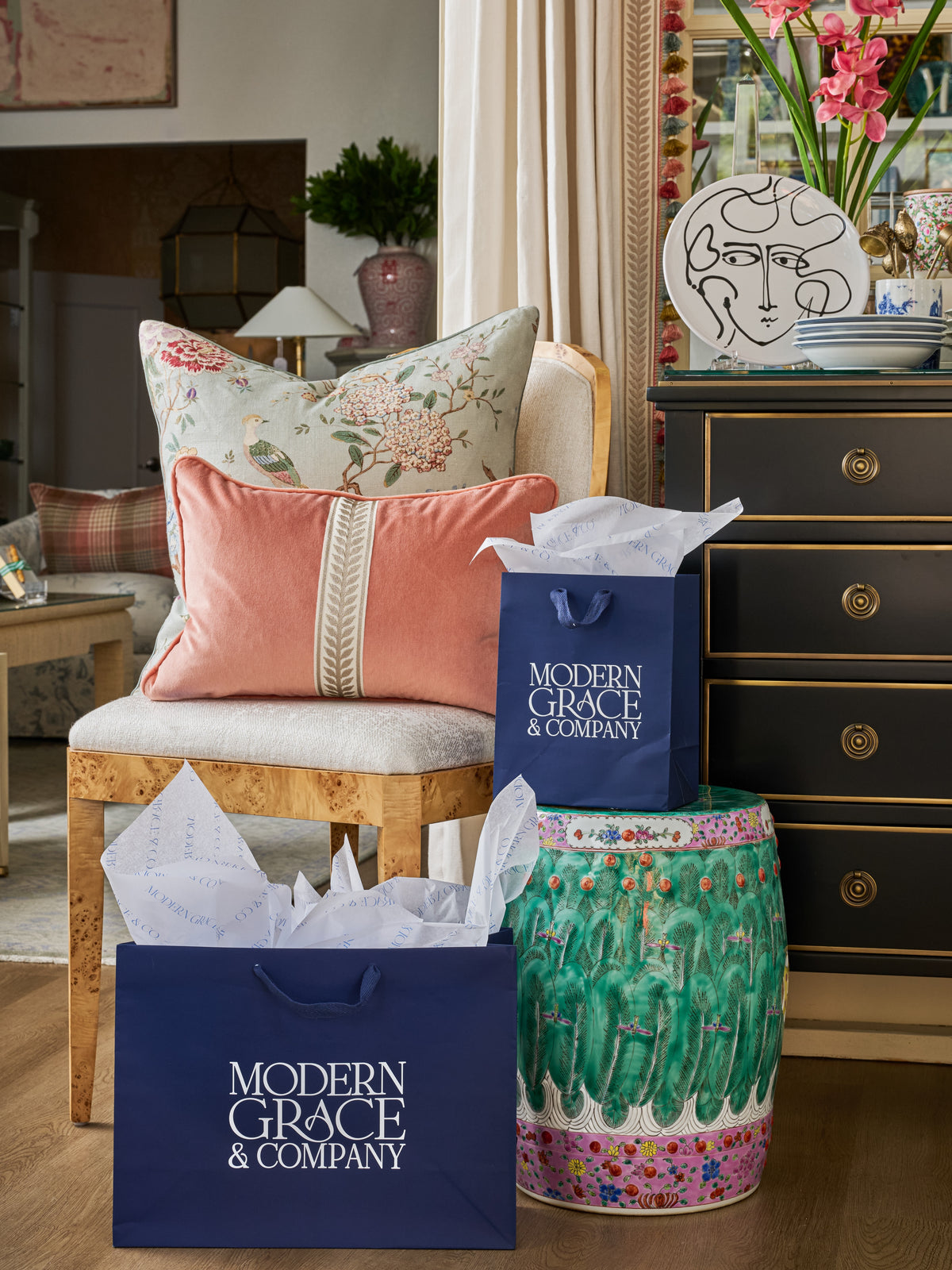 Floral and coral accent pillows layered on an upholstered chair at Modern Grace & Co.